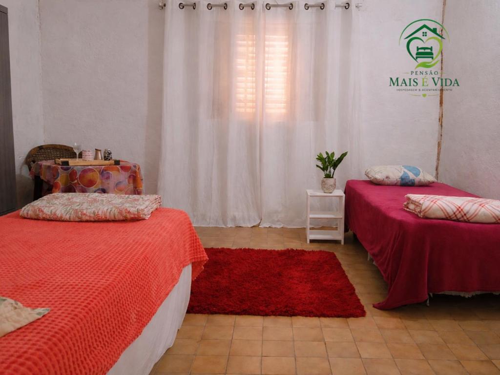 a bedroom with two beds and a red rug at Pousada Mais E Vida 24h in Teresina