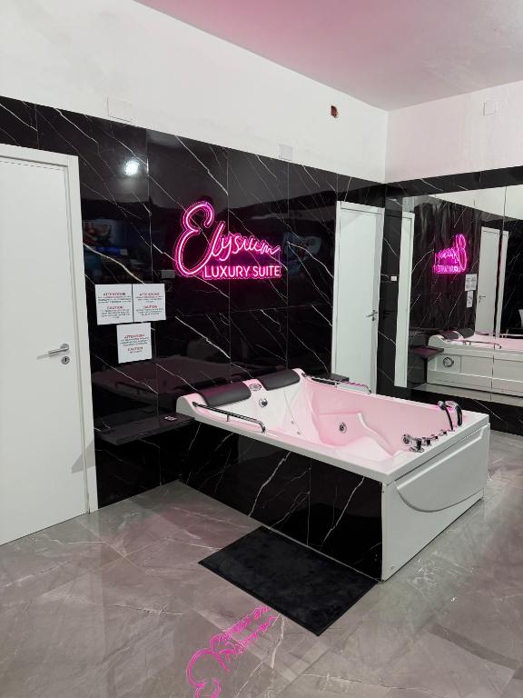 a pink bath tub in a bathroom with a pink sign at Elysium Luxury Suite in Trabia