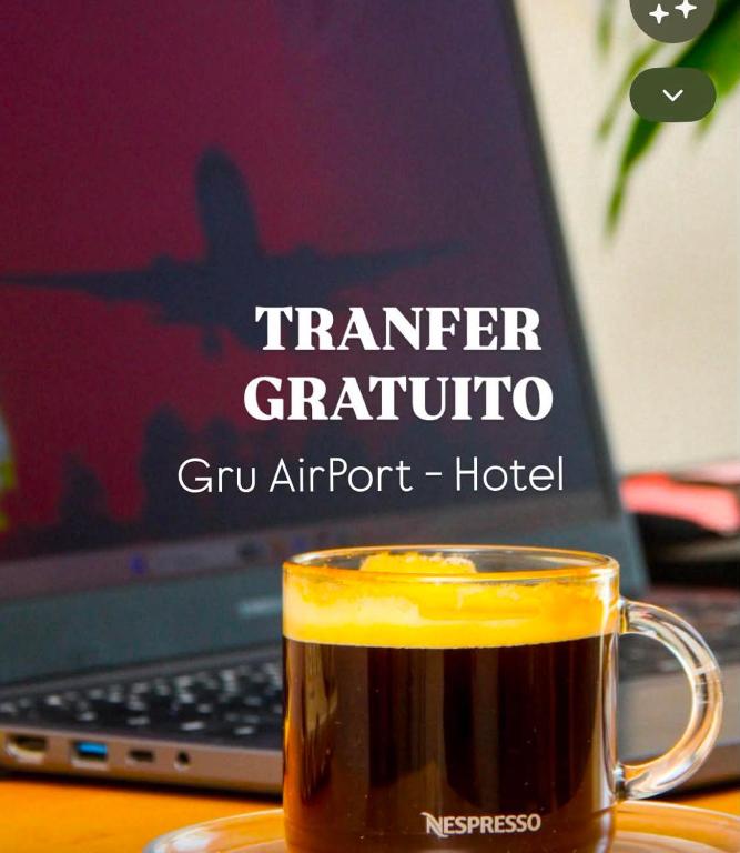 a cup of coffee on a table next to a laptop at Flat Executivo GRU Airport in Guarulhos