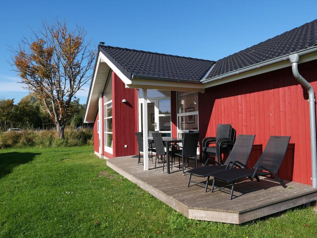 a group of chairs sitting on a deck next to a red building at Grobenbrode Split-Wing House in Grossenbrode