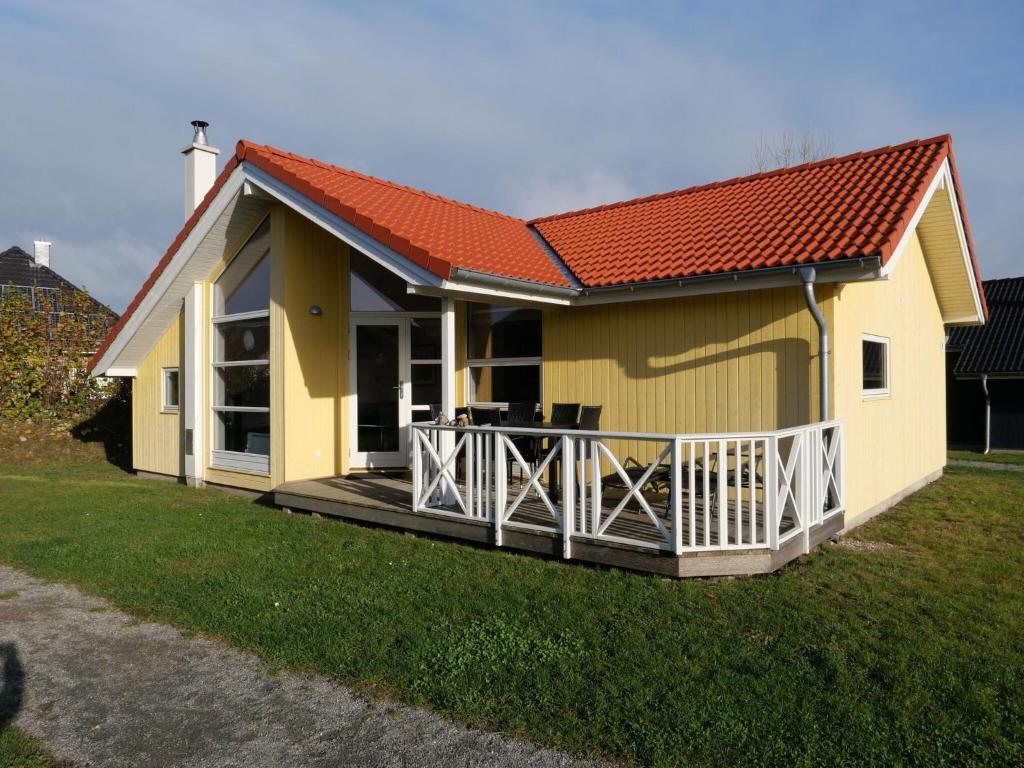 a small yellow house with a wooden deck at Spa Cottage with Two Wings in Grossenbrode