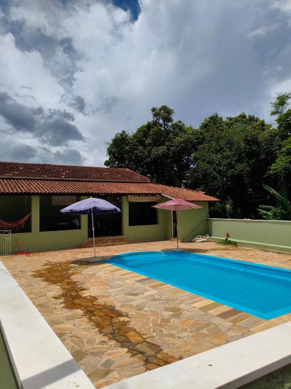 a swimming pool with two umbrellas next to a house at Chácara Angola in Andradas