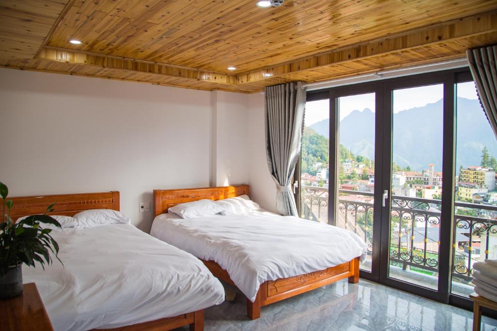two beds in a room with a balcony at Sapa Station Hotel in Sapa