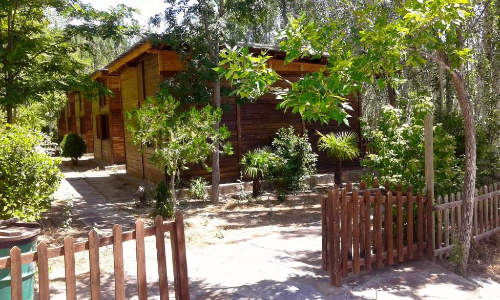 uma cabana de madeira com uma cerca em frente em Camping Alpujarras em Laroles