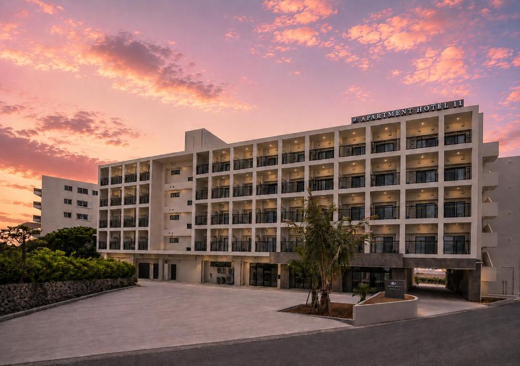 an office building with a sunset in the background at Apartment Hotel 11 Miyakojima in Miyako-jima