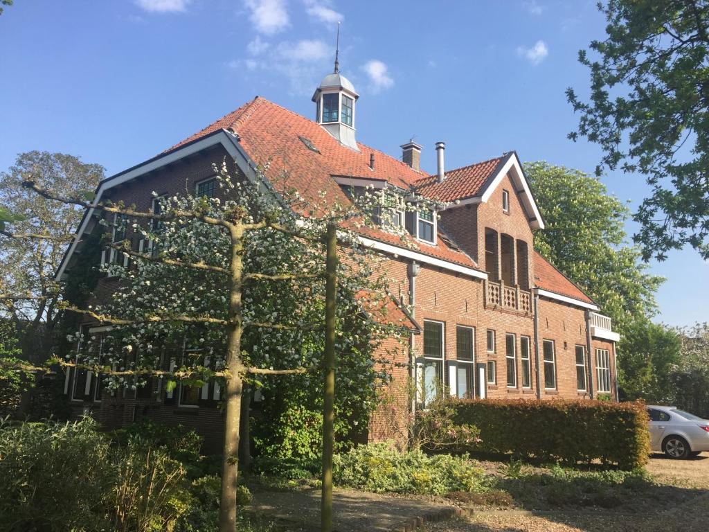 un gran edificio de ladrillo con una torre encima en Seulle State, en Sint Jacobiparochie