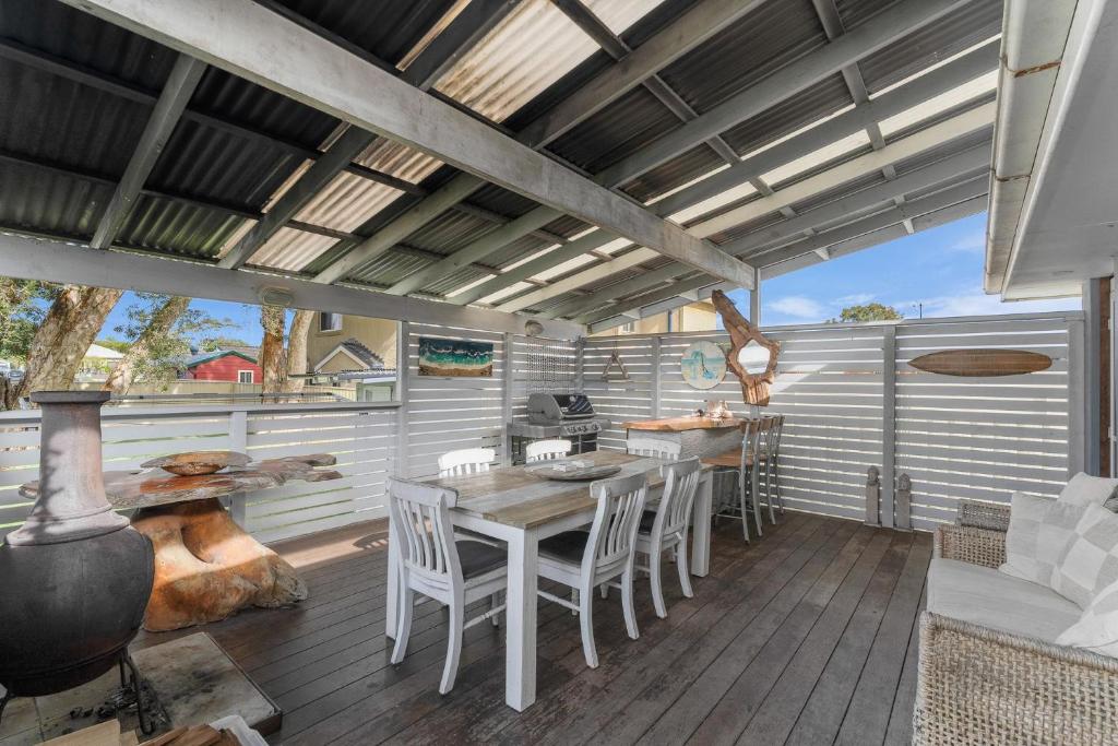 a patio with a table and chairs on a deck at Blue Summer House in Long Jetty