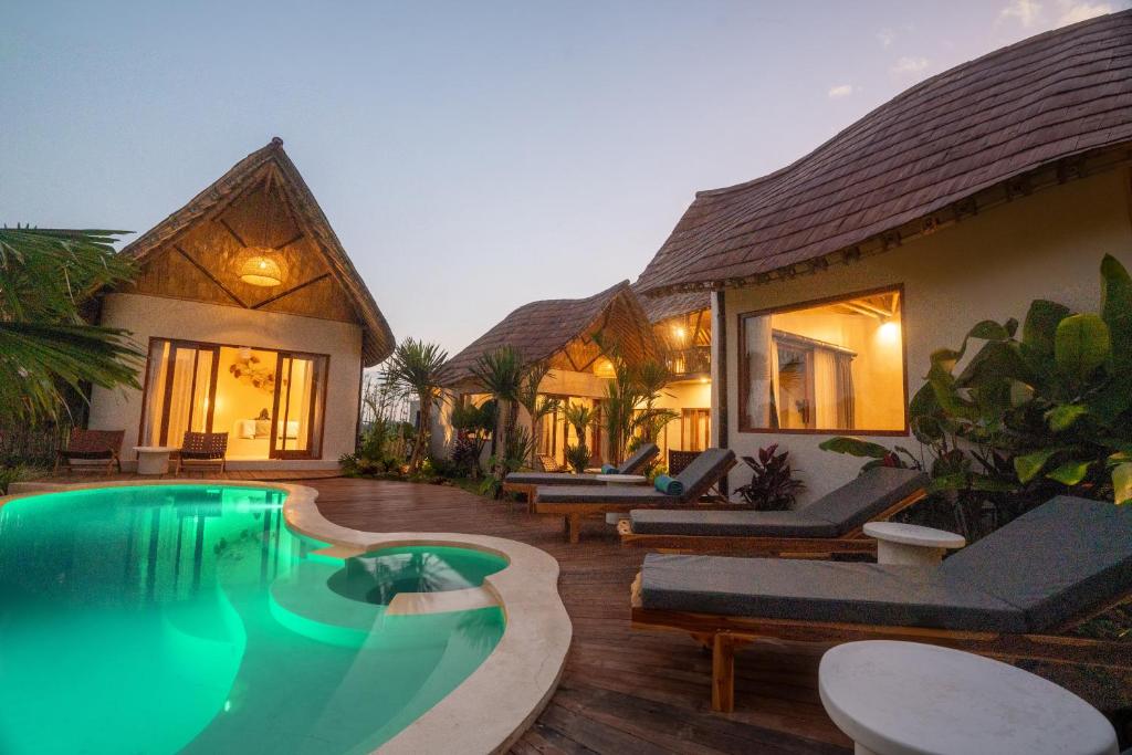 a villa with a swimming pool in front of a house at Bamboo Layang Ubud in Ubud