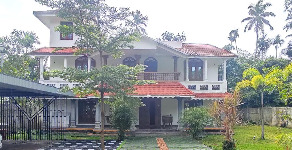 a large white house with a red roof at Casa de Victoria in Alleppey