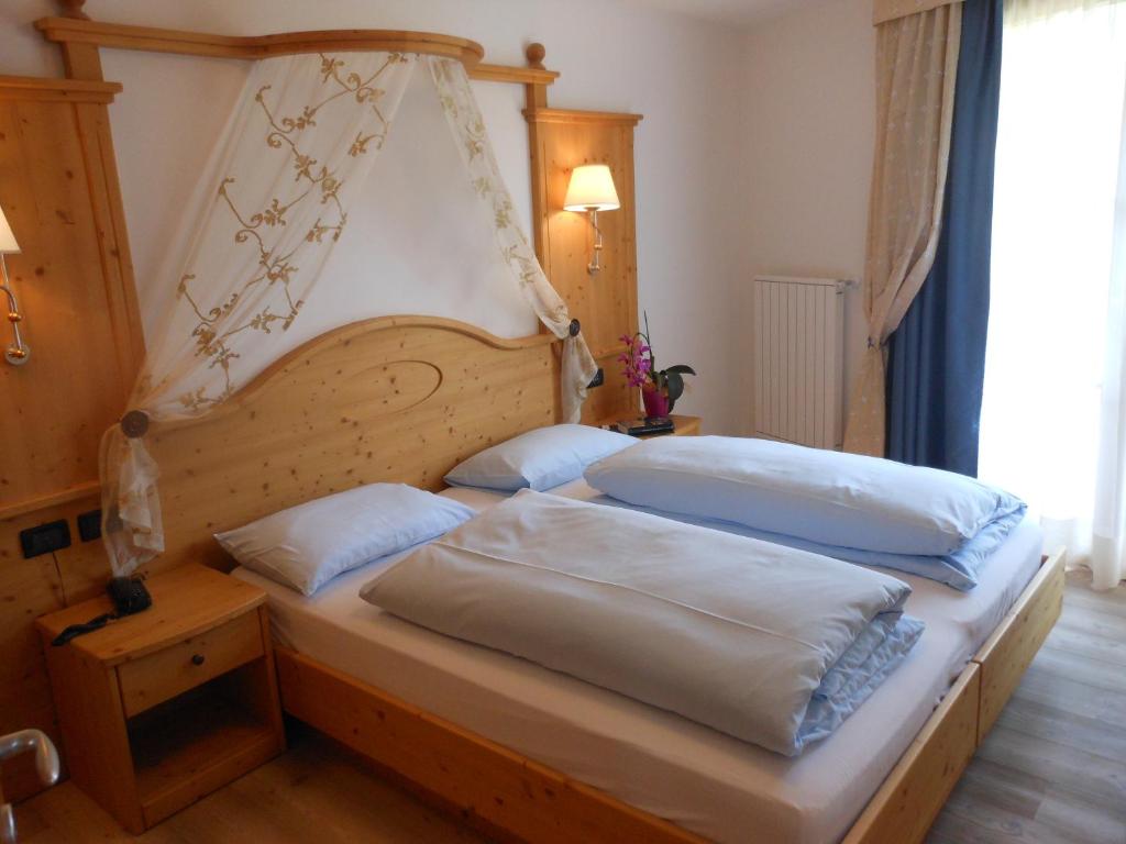 Schlafzimmer mit einem Bett mit einem Kopfteil aus Holz in der Unterkunft Il Falchetto in Sarnonico