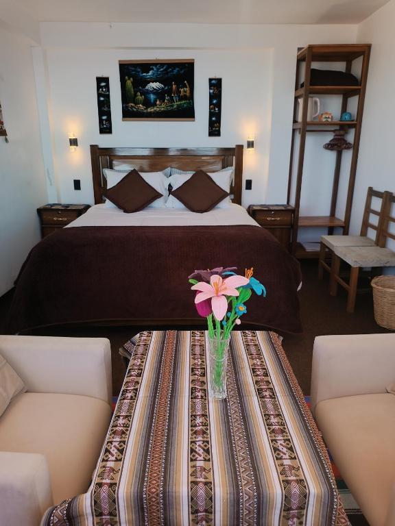 a bedroom with a bed with a vase of flowers on a table at Sol y Luna in Comunidad Yumani