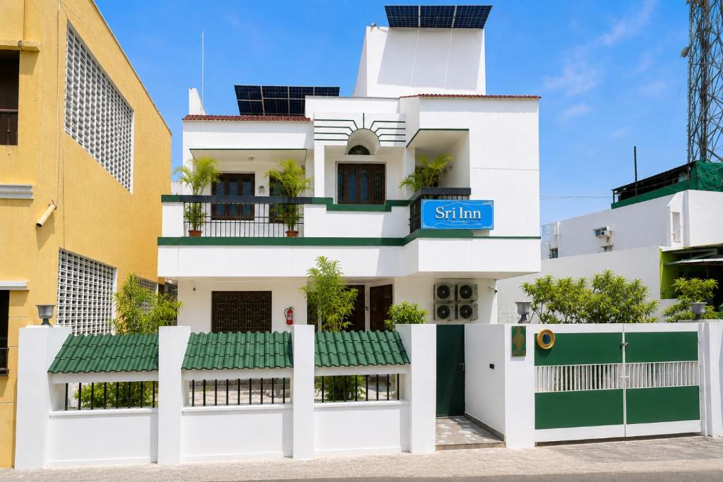 a white building with a blue sign on it at Sri Inn in Pondicherry
