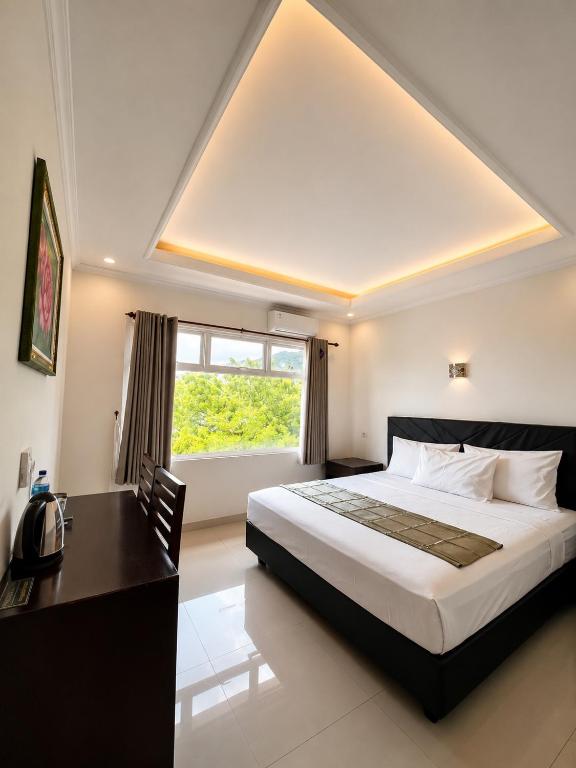 a bedroom with a bed and a desk and a window at Anugrah Hotel Teluk Nara in Teluknarat