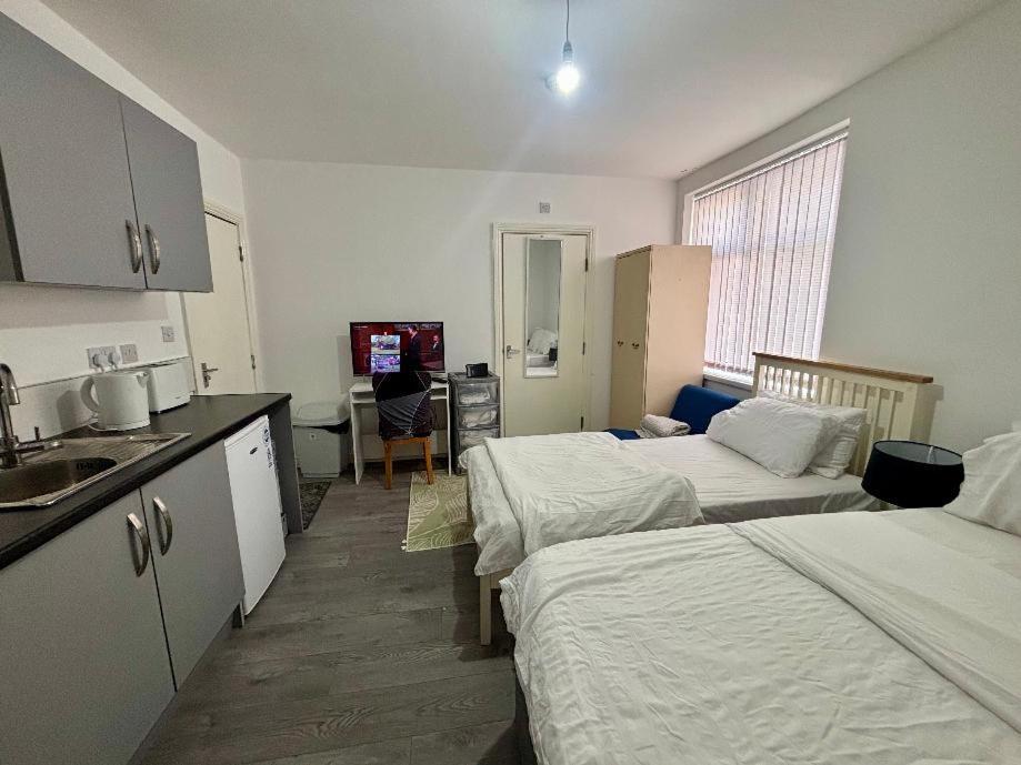 a room with two beds and a kitchen with a sink at HomesRentals Studio in Dudley
