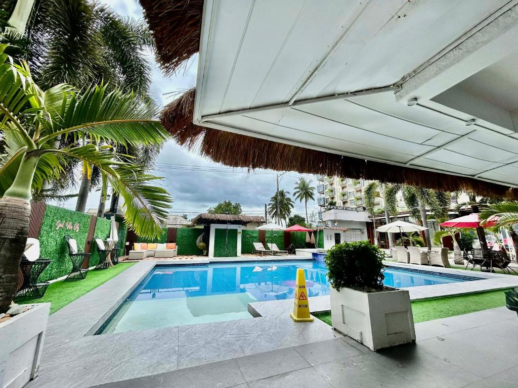 a swimming pool with an umbrella and some chairs and trees at At The Pad Hotel & Villa's in Angeles