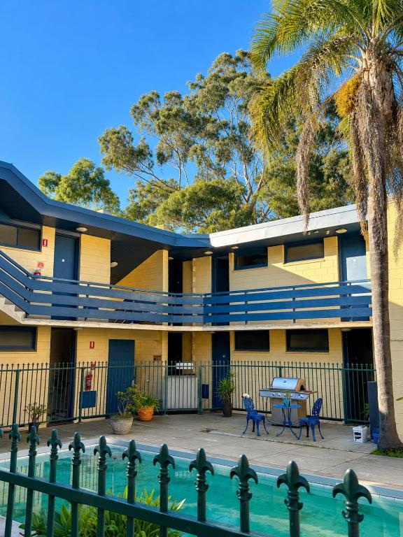 a building with a pool and palm trees at Pathfinder Motel in Melbourne