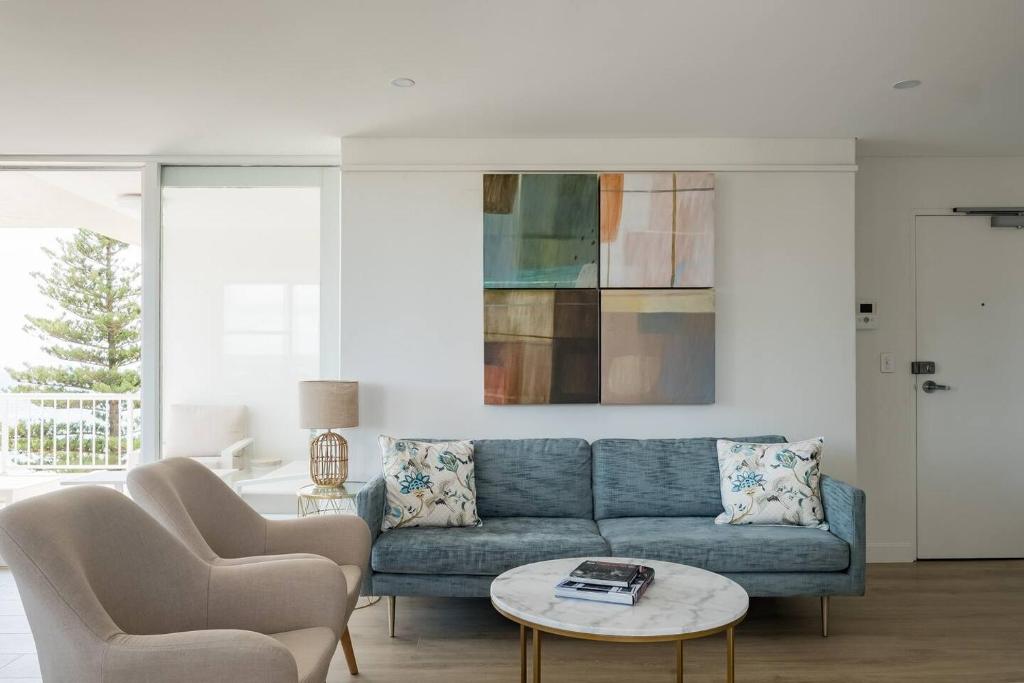 a living room with a blue couch and two chairs at Stunning Beachfront penthouse-Beach District Views in Sydney