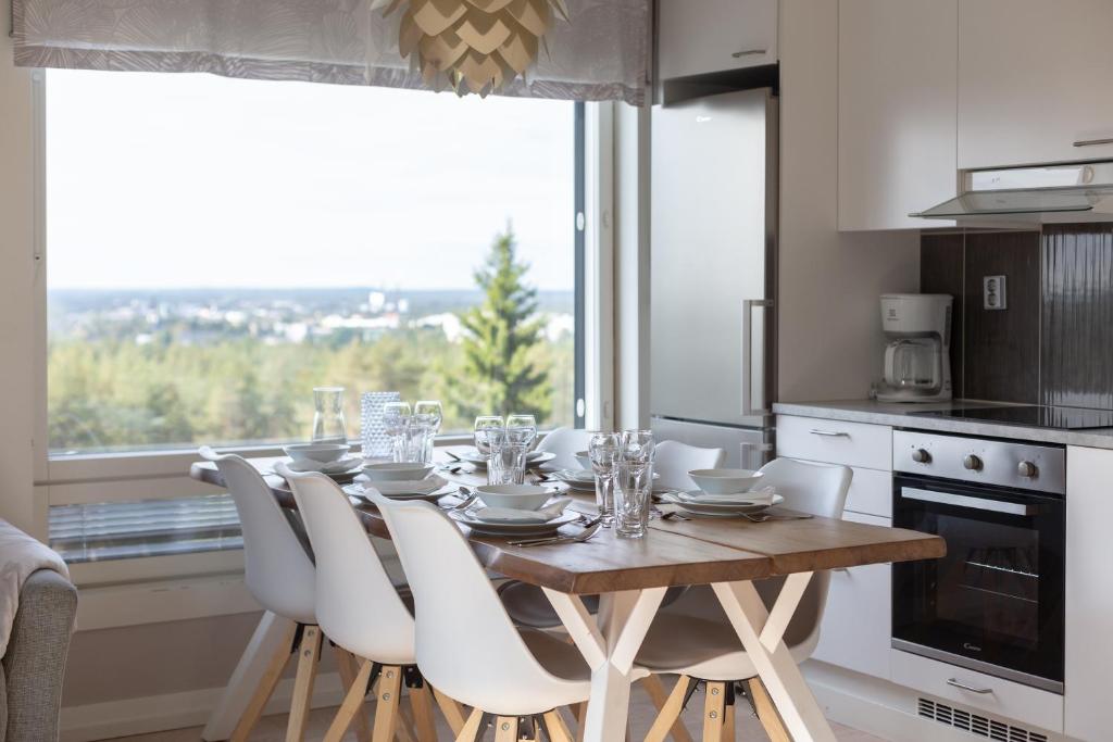 a dining room table with white chairs and a kitchen at Santasport Apartment Hotel in Rovaniemi