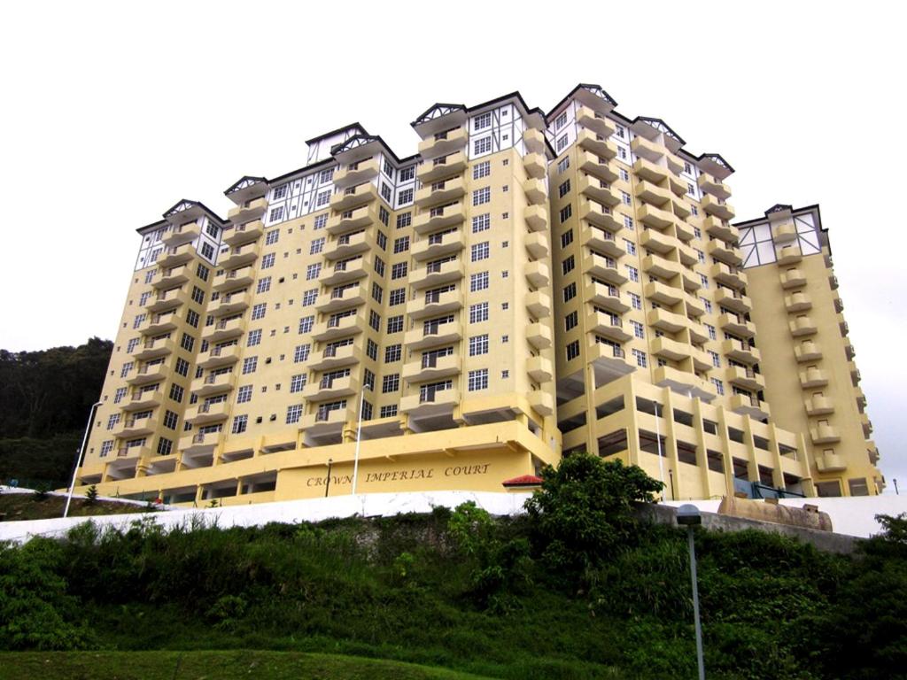 un gran edificio de apartamentos amarillo en la cima de una colina en Cameron View Apartment @ Crown Imperial Court Brinchang, en Cameron Highlands