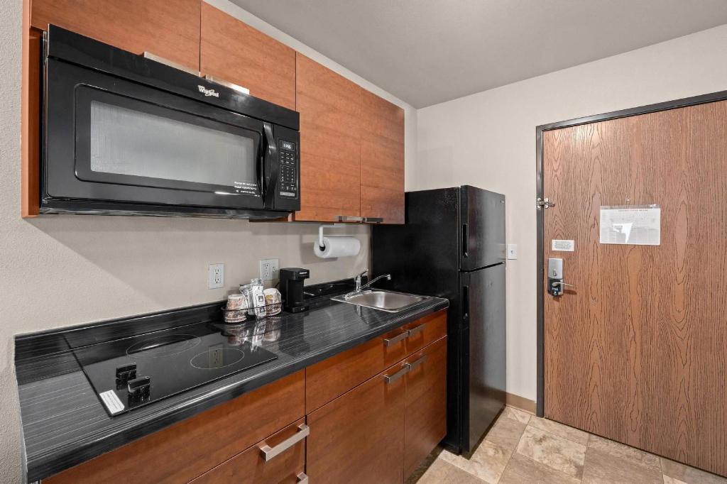 a kitchen with a sink and a black refrigerator at MainStay Suites Spokane Valley in Spokane Valley