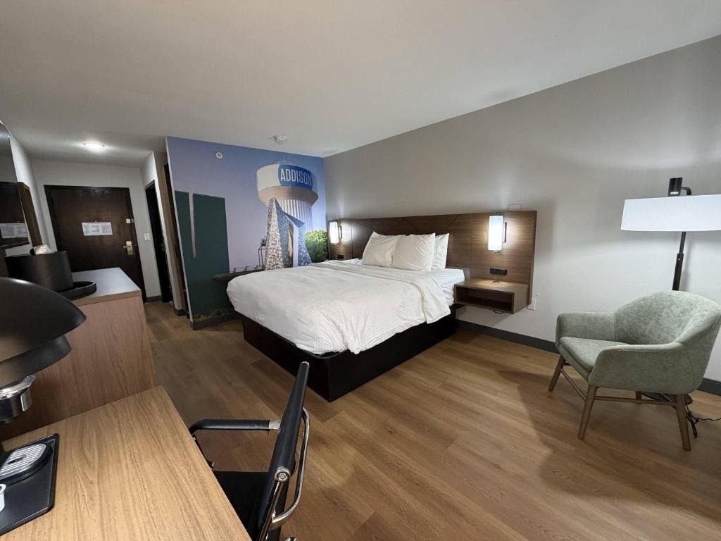 a hotel room with a bed and a chair at Clarion Pointe Addison - Dallas North in Addison