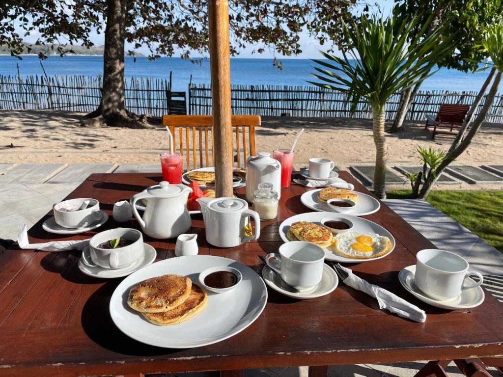 a wooden table with breakfast food on top of the beach at Starsand Beach Resort in Sekotong
