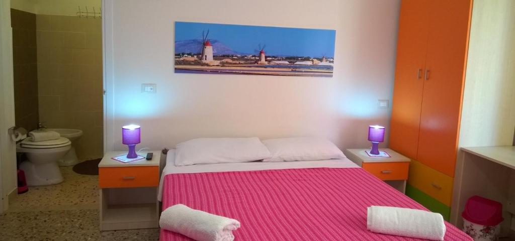 1 dormitorio con 1 cama con sábanas rosas y lámparas púrpuras en Afrodite Trapani en Trapani