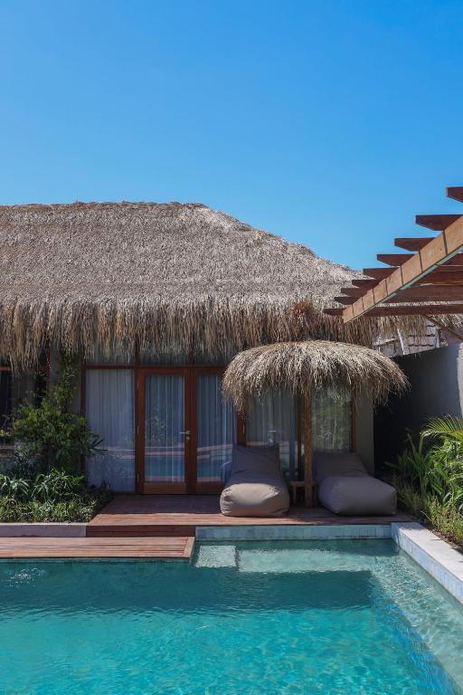 a resort with a swimming pool and a straw hut at Amel - Soft Opening in Gili Islands