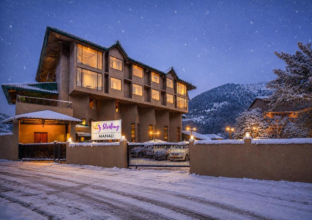 a building with a sign in the snow at night at Sterling Manali in Manāli