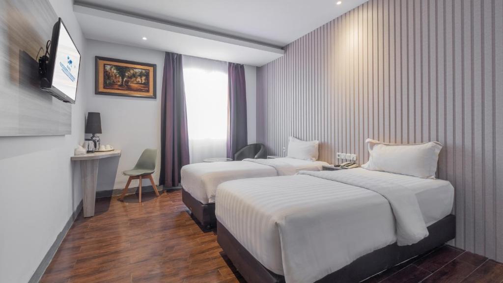 a hotel room with two beds and a desk at Continent CentrePoint Makassar in Pampang
