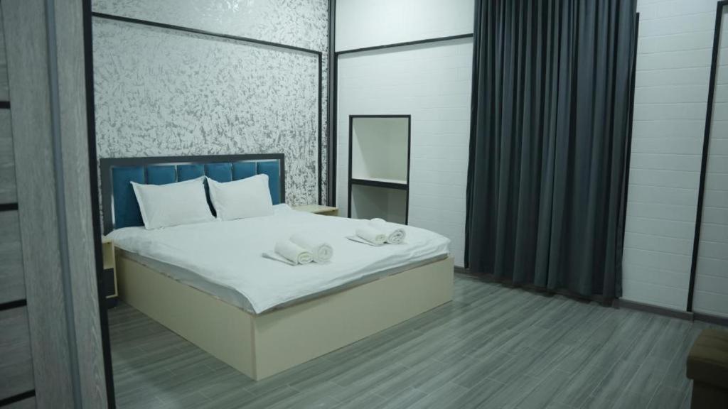 a bedroom with a bed with white sheets and a mirror at Hotel City Land Tashkent in Yakkasaray