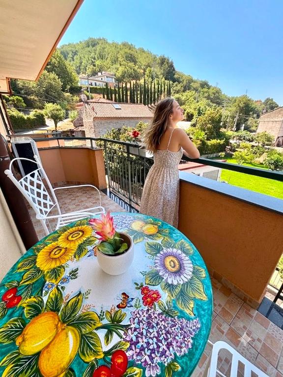 a woman standing on a balcony with a table at Luxury Apartment nel Cilento - 10 min da Ascea e mare, WiFi & parcheggio in Castelnuovo Cilento