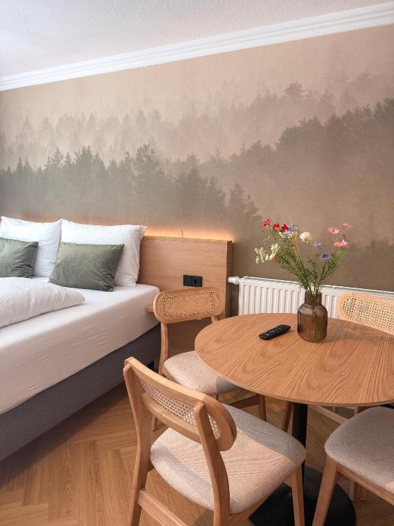 a bedroom with a bed and a table with chairs at ALPURA Allgäu - Active Nature Retreat - HOTEL REOPENING in Bad Hindelang