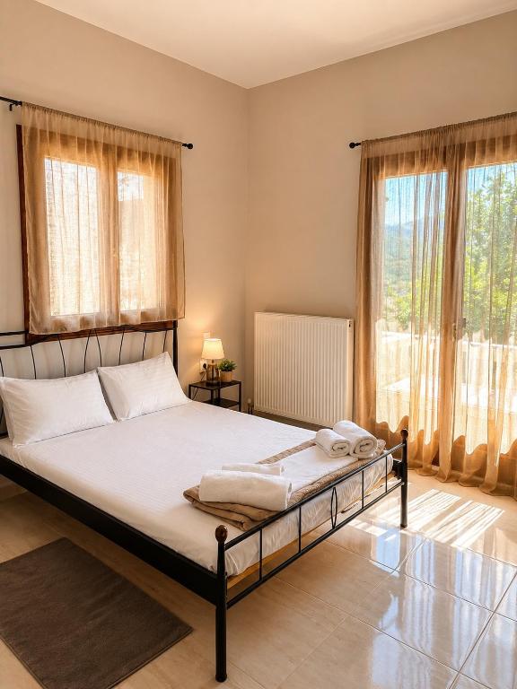 a bedroom with a bed with white sheets and windows at Villa Rozalia in Konitsa