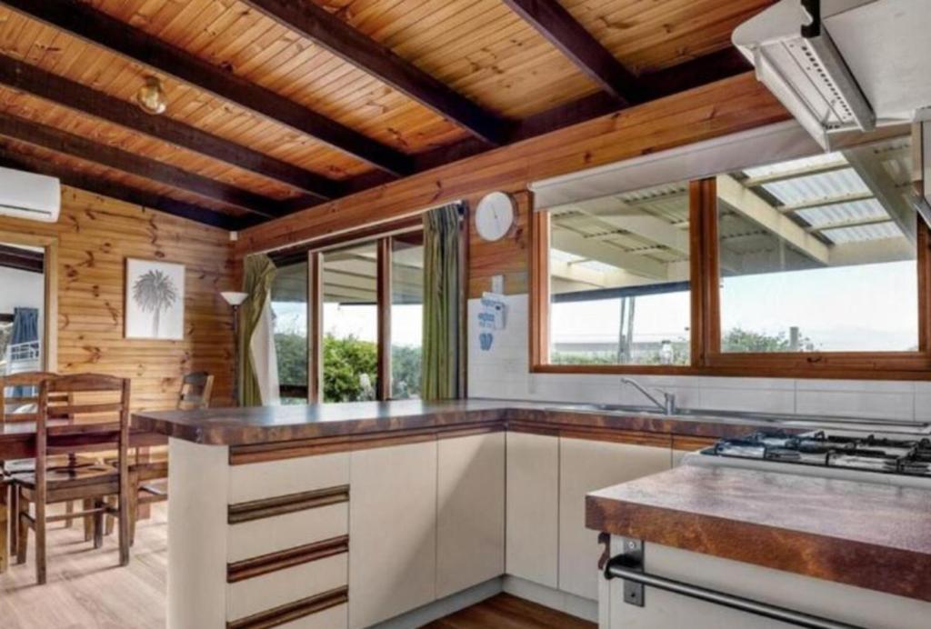 a kitchen with white cabinets and a table and some windows at Sun, Sand, and Tranquility in Rye in Rye