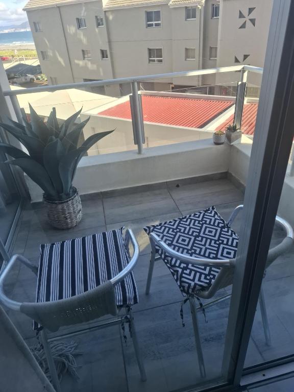 a balcony with a chair and a table and a plant at Blouberg Beach Escape in Cape Town