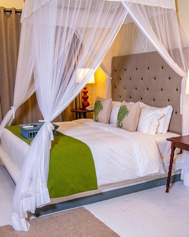 a bedroom with a white bed with a canopy at udesh hotel in Minuwangoda