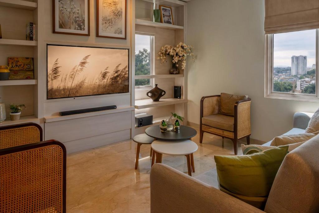 a living room with a tv and a couch and a table at Dago Suite 3BR Luxury Apartment in Bandung