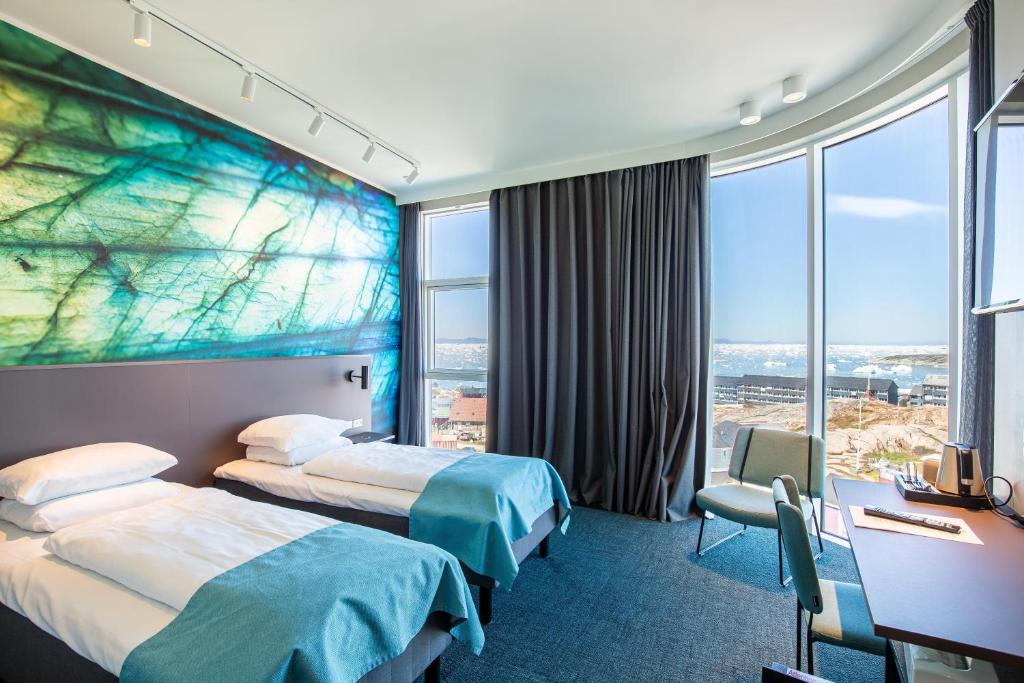 a hotel room with two beds and a large window at Best Western Plus Hotel Ilulissat in Ilulissat