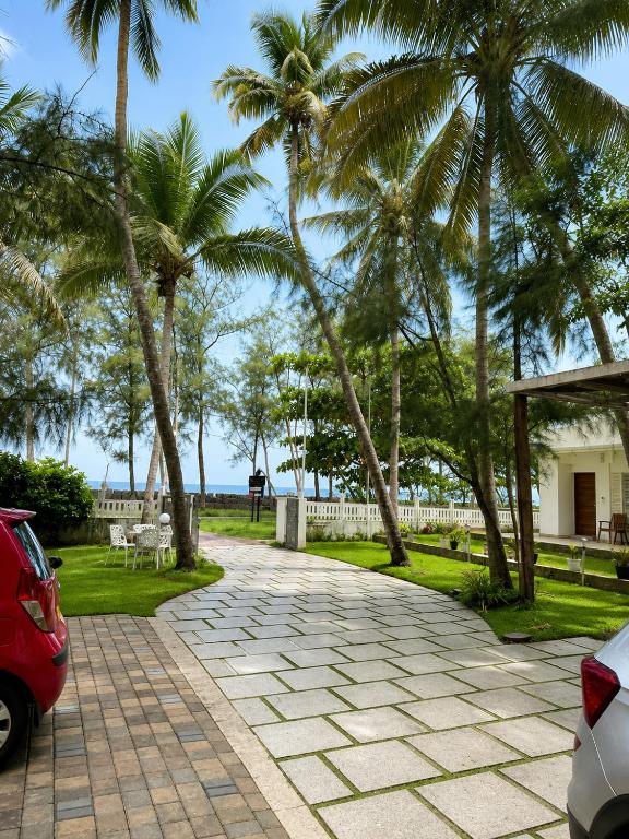 a driveway with palm trees and a red car at Vedic villa Cherai beach in Cochin