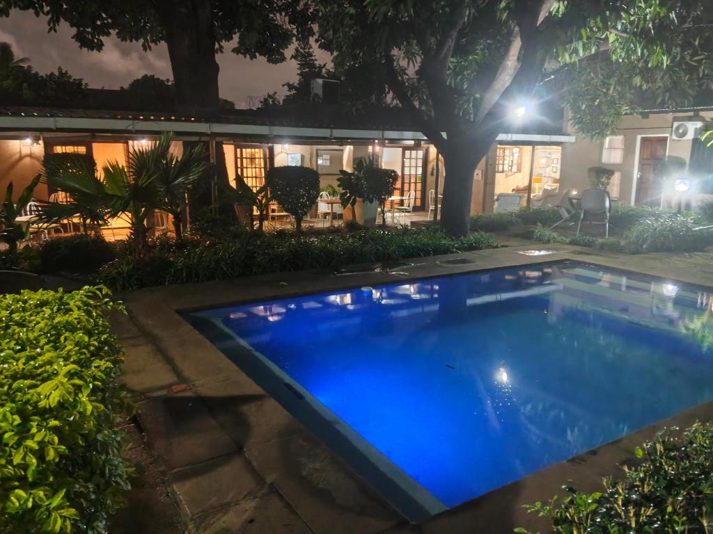 a swimming pool in front of a house at night at The Courtyard Guesthouse in Matola