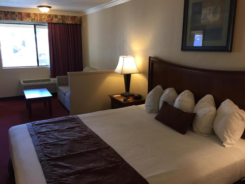 a hotel room with a large bed and a lamp at Chula Vista Inn in Chula Vista