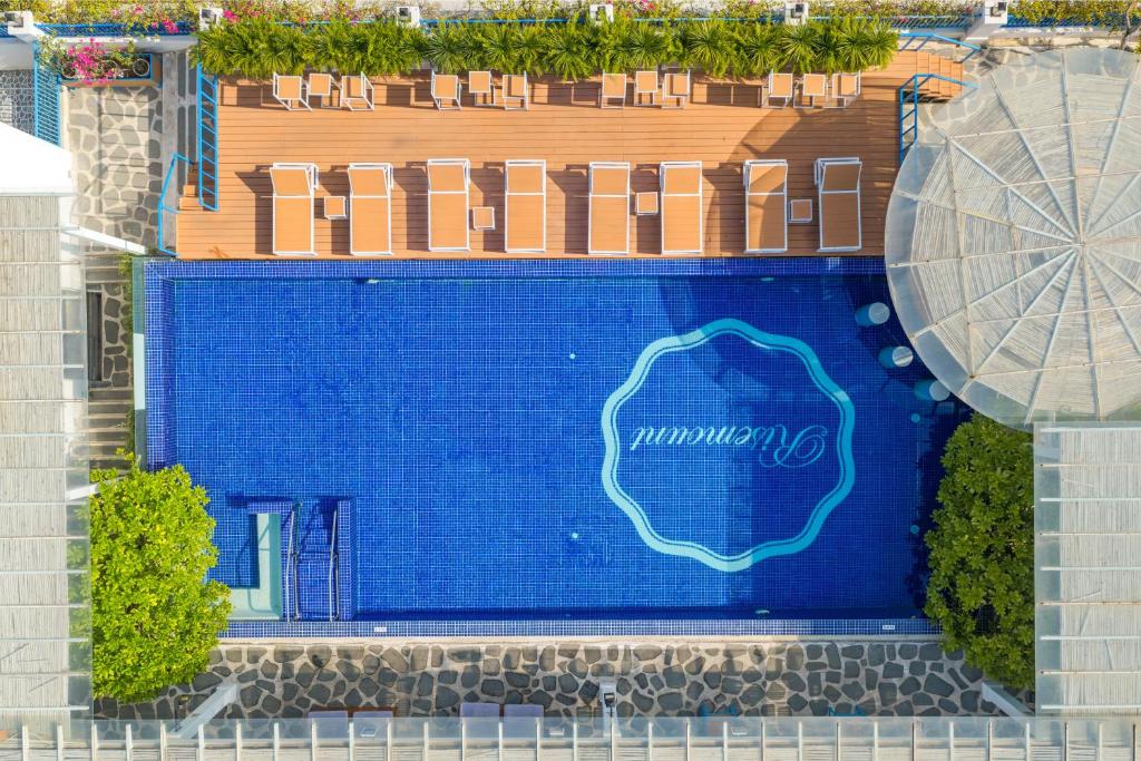 A top-down view of a rectangular rooftop pool surrounded by loungers and a large shade canopy.