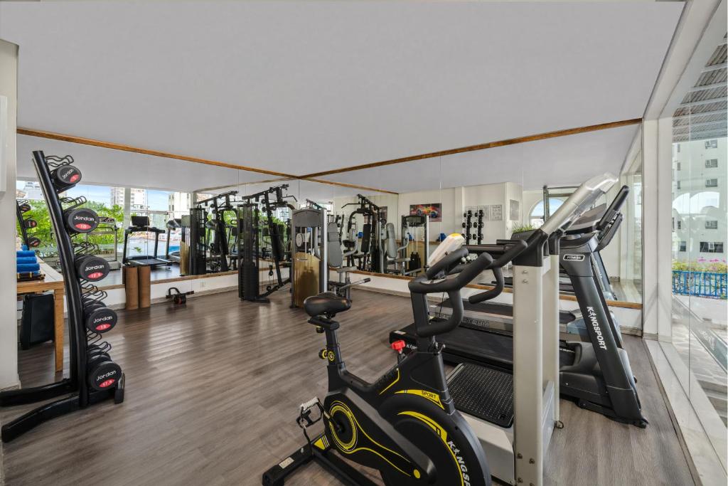 A compact, brightly lit gym with cardio machines, weight equipment and mirrored walls.