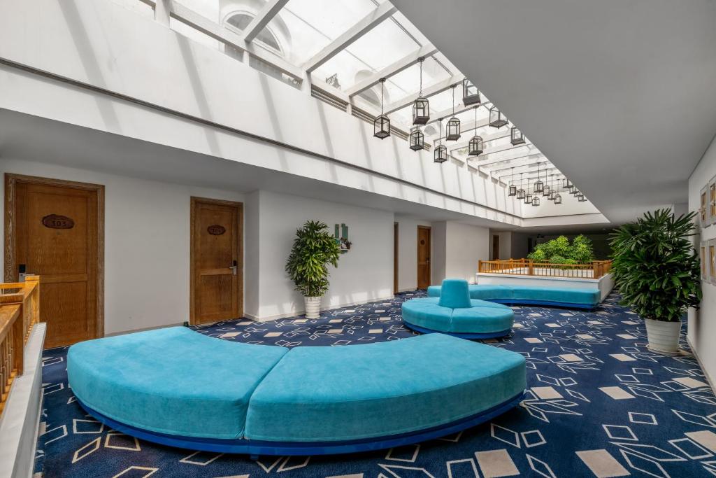 A bright interior corridor with oversized turquoise seating and hotel room doors.