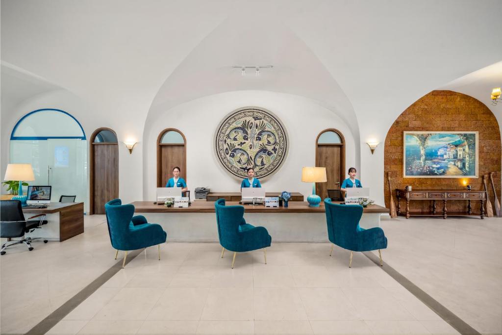 A formal lobby reception with teal lounge chairs, a long desk and arched architectural details.