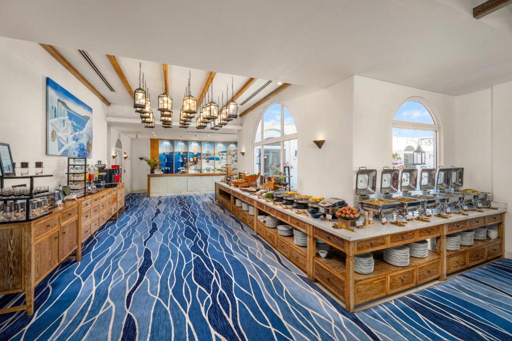 A bright buffet breakfast room with blue patterned carpeting and tall arched windows.