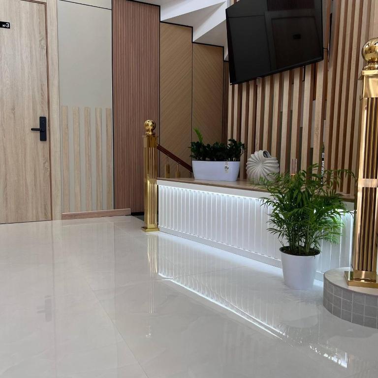 a lobby with a staircase with potted plants and a television at Maftun Guest House in Samarkand