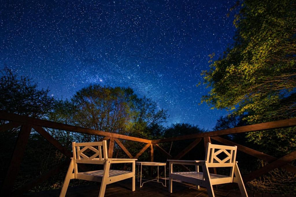 two chairs sitting on a deck under a starry sky at Suite Villa Panora Yatsugatake in Minamimaki