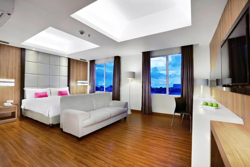 パダンにあるfavehotel Olo Padangのベッドルーム(白いベッド1台、ソファ付)